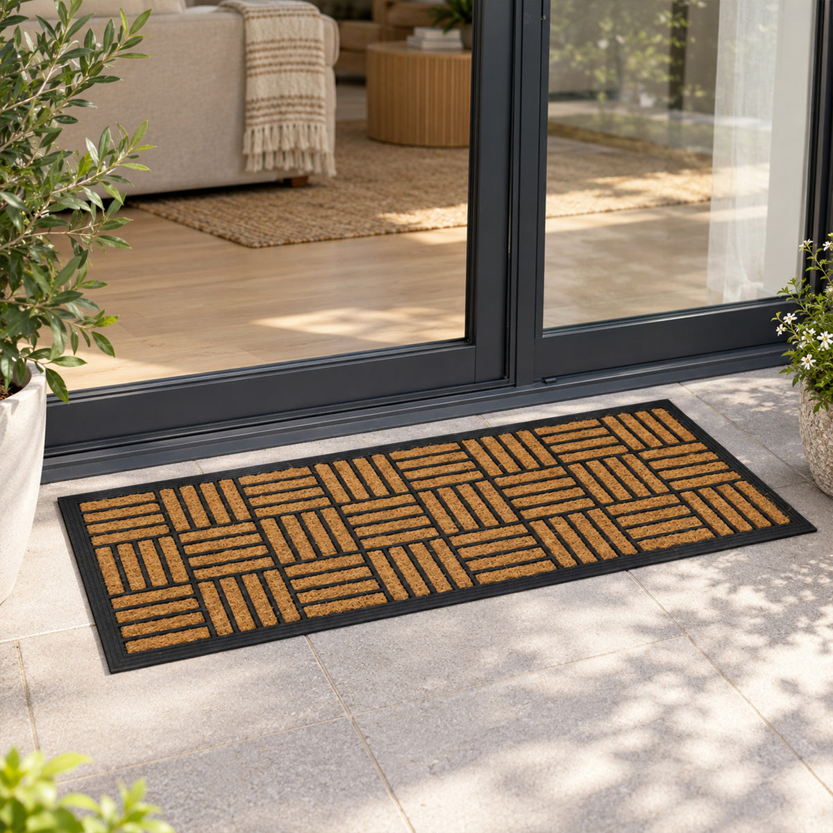 Fieldcrest Checkers Ranch Coir Mat in natural, featuring a black geometric checkerboard pattern, placed on a tiled outdoor patio in front of a black-framed ranch slider door.