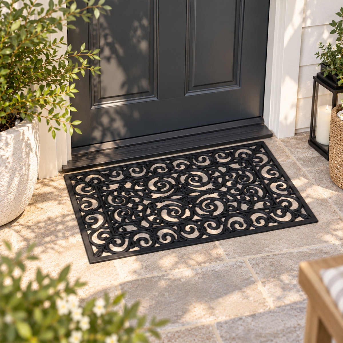 Design Republique Gabriel Rubber Mat in black, featuring decorative scrollwork, placed on a tiled outdoor entranceway in front of a black door.