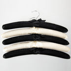 Home Essentials Padded Hangers 5 Pack Black & Cream featuring black and cream satin padded hangers with ribbon details.