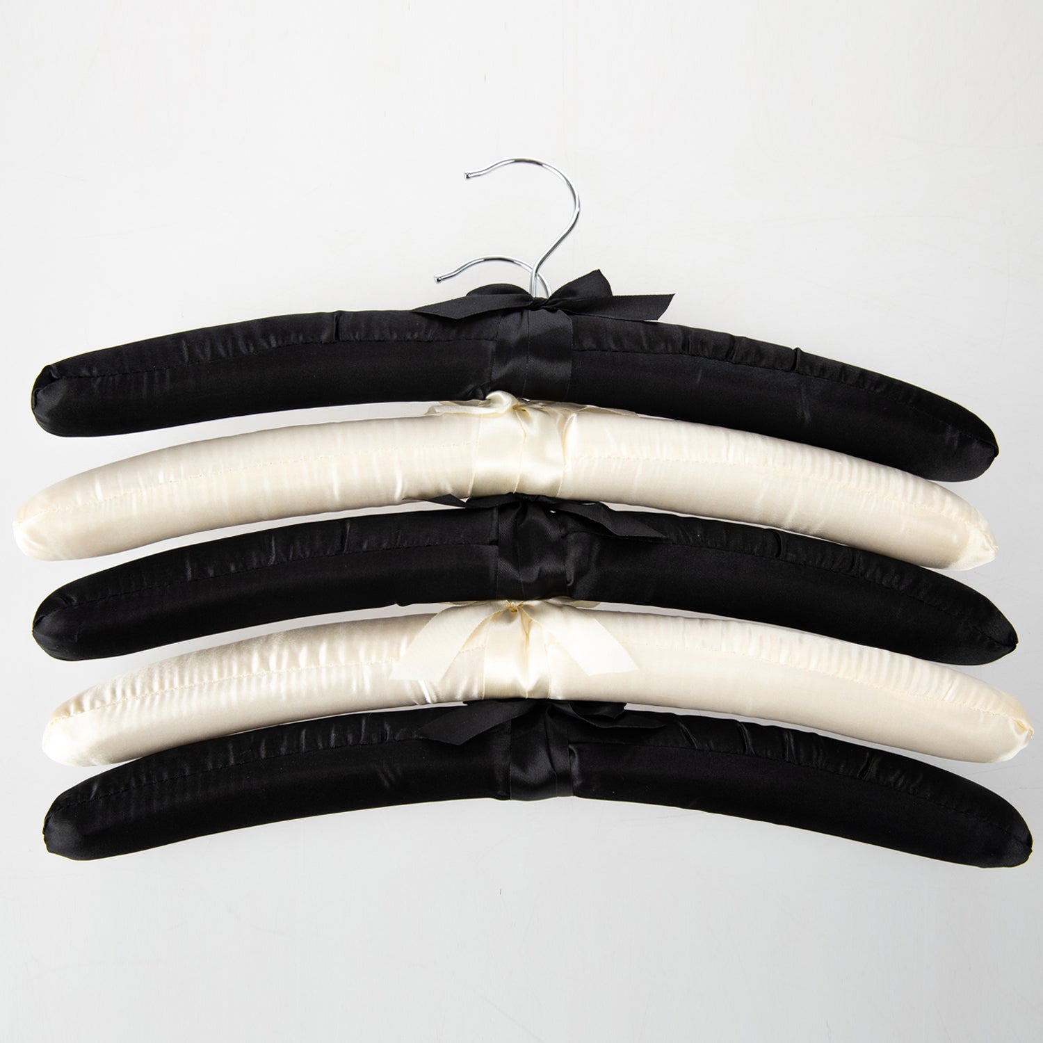 Home Essentials Padded Hangers 5 Pack Black & Cream featuring black and cream satin padded hangers with ribbon details.