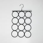 A black metal wall-mounted ring hanger with a single hook at the top and twelve circular ring slots arranged in a grid, shown against a plain white background.