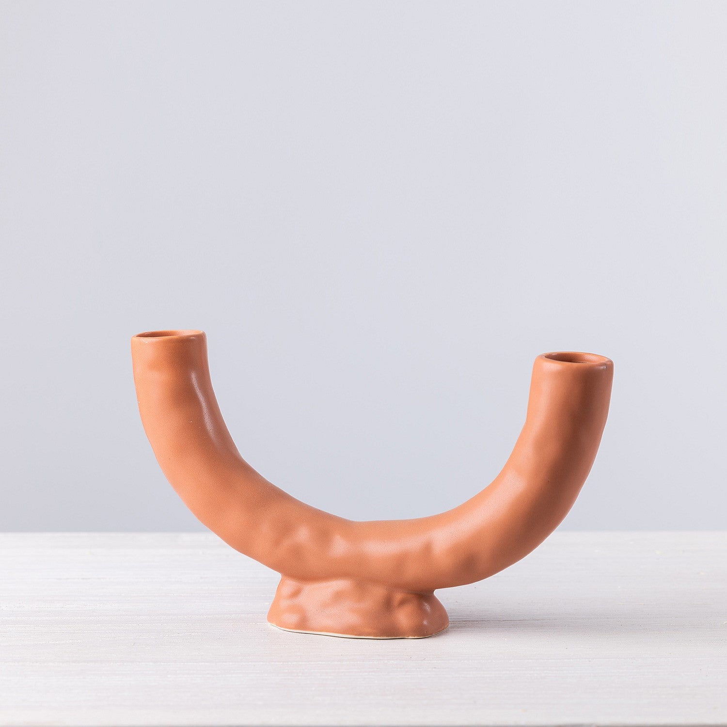 Ceramic vase with a unique design on a white surface and light gray background