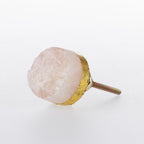 Rose quartz crystal drawer knob with natural rough-cut stone finish, gold-tone edging and metal screw fitting.
