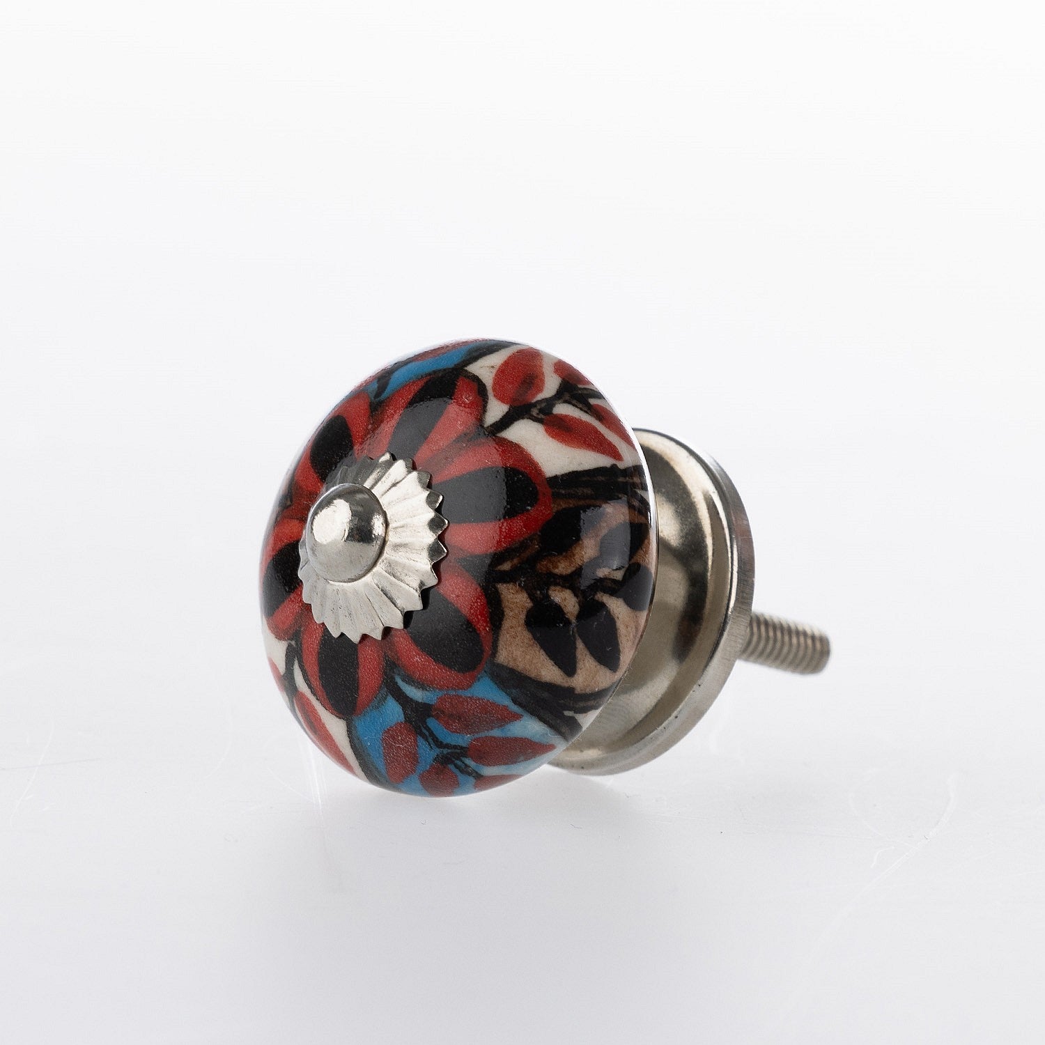 Round ceramic drawer knob with red, blue and black floral pattern detailing and silver metal centre accent.
