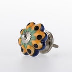 Flower-shaped ceramic drawer knob with yellow, green and navy floral pattern detailing and silver metal centre accent.
