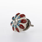 White flower-shaped ceramic drawer knob with red and blue floral pattern detailing and silver metal centre accent.
