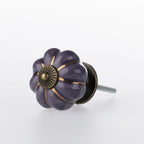 Purple flower-shaped ceramic drawer knob with bronze-tone centre detail, metallic gold stripe accents and a glossy finish.
