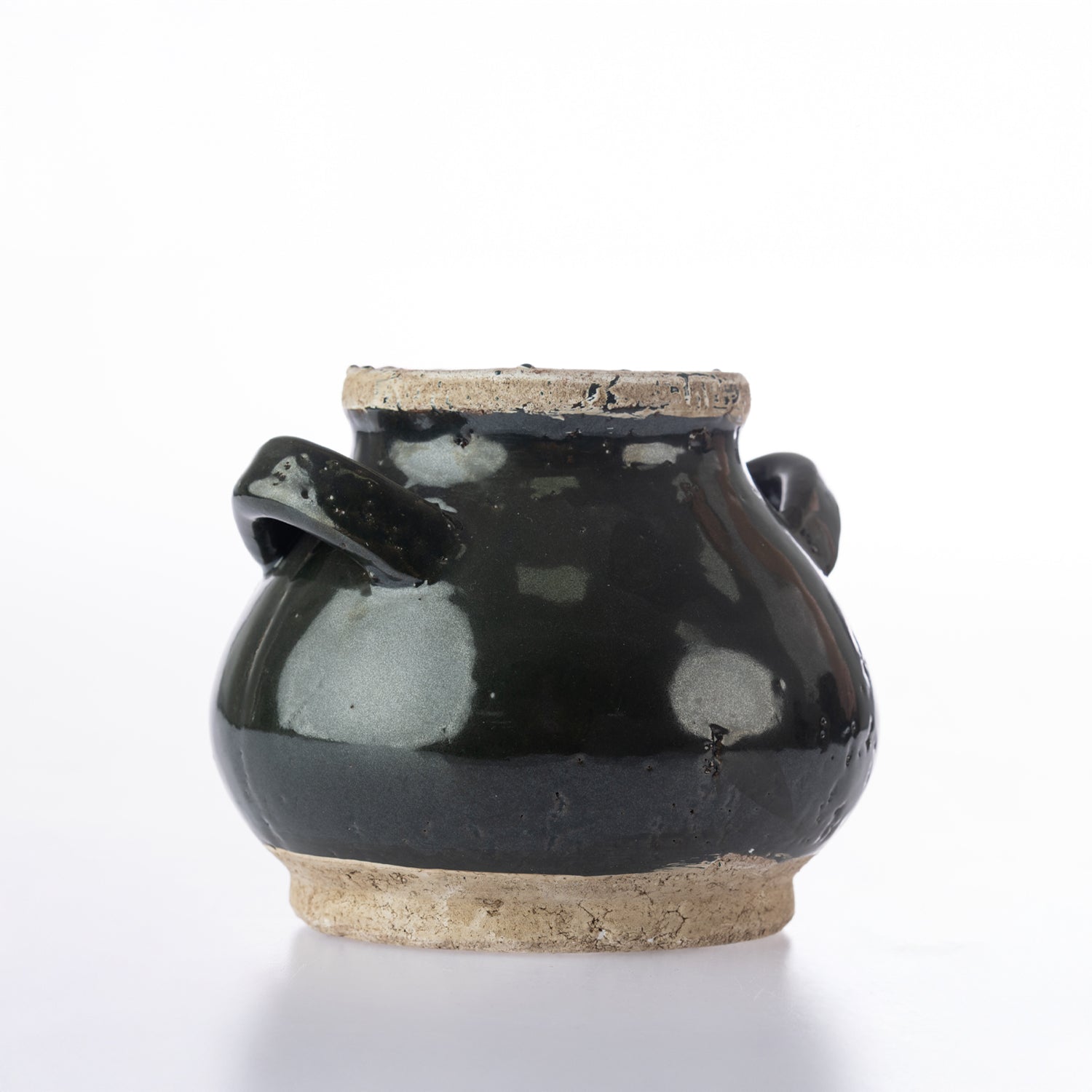 A small handmade ceramic pot with a glossy black glaze and natural beige clay base, featuring two side handles, photographed on a white background.