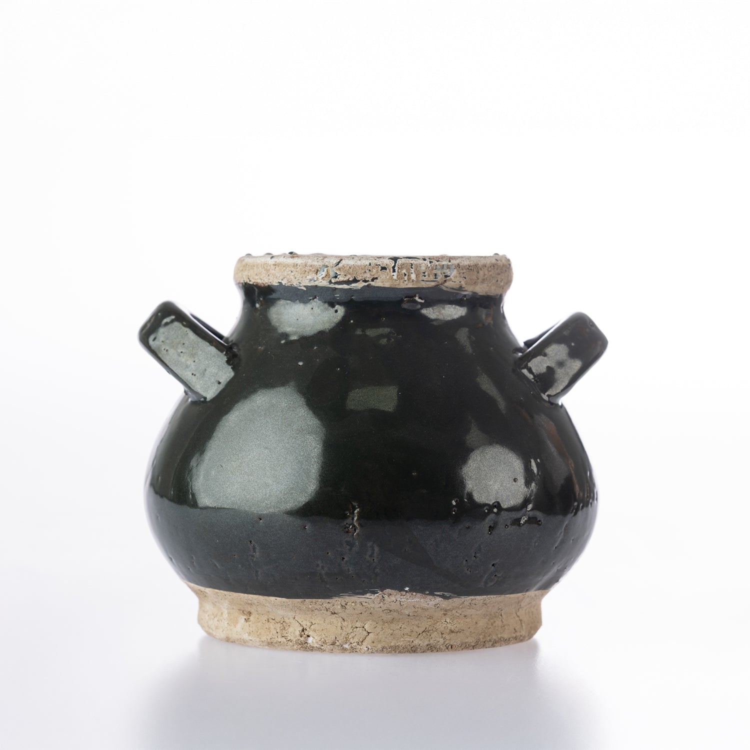 A small handmade ceramic pot with a glossy black glaze, featuring two side handles, a natural clay rim, and an exposed clay base, photographed on a white background.