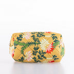 Quilted floral cosmetic bag in a mustard yellow print with zip closure and structured shape.
