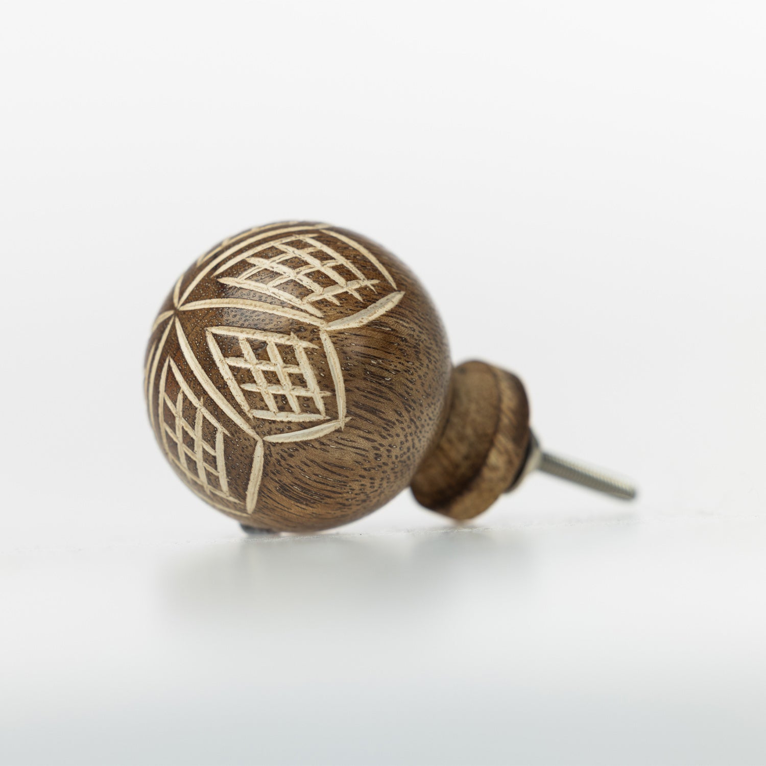 Brown wooden round drawer knob with engraved geometric leaf pattern and metal screw fitting.
