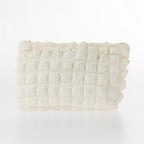 Cream textured waffle cosmetic pouch with soft padded finish and zip closure on a white background.