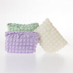Textured waffle cosmetic pouches in mint, lilac, and cream displayed together on a white background.