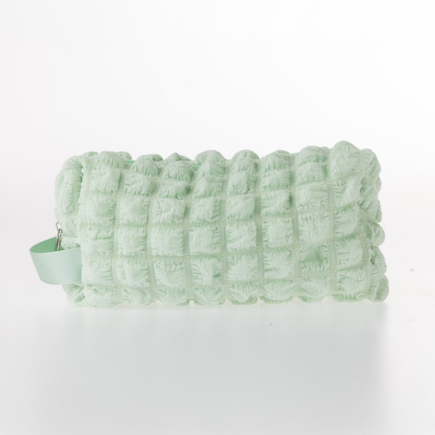 Green textured waffle toiletry bag with zip closure on a white background.