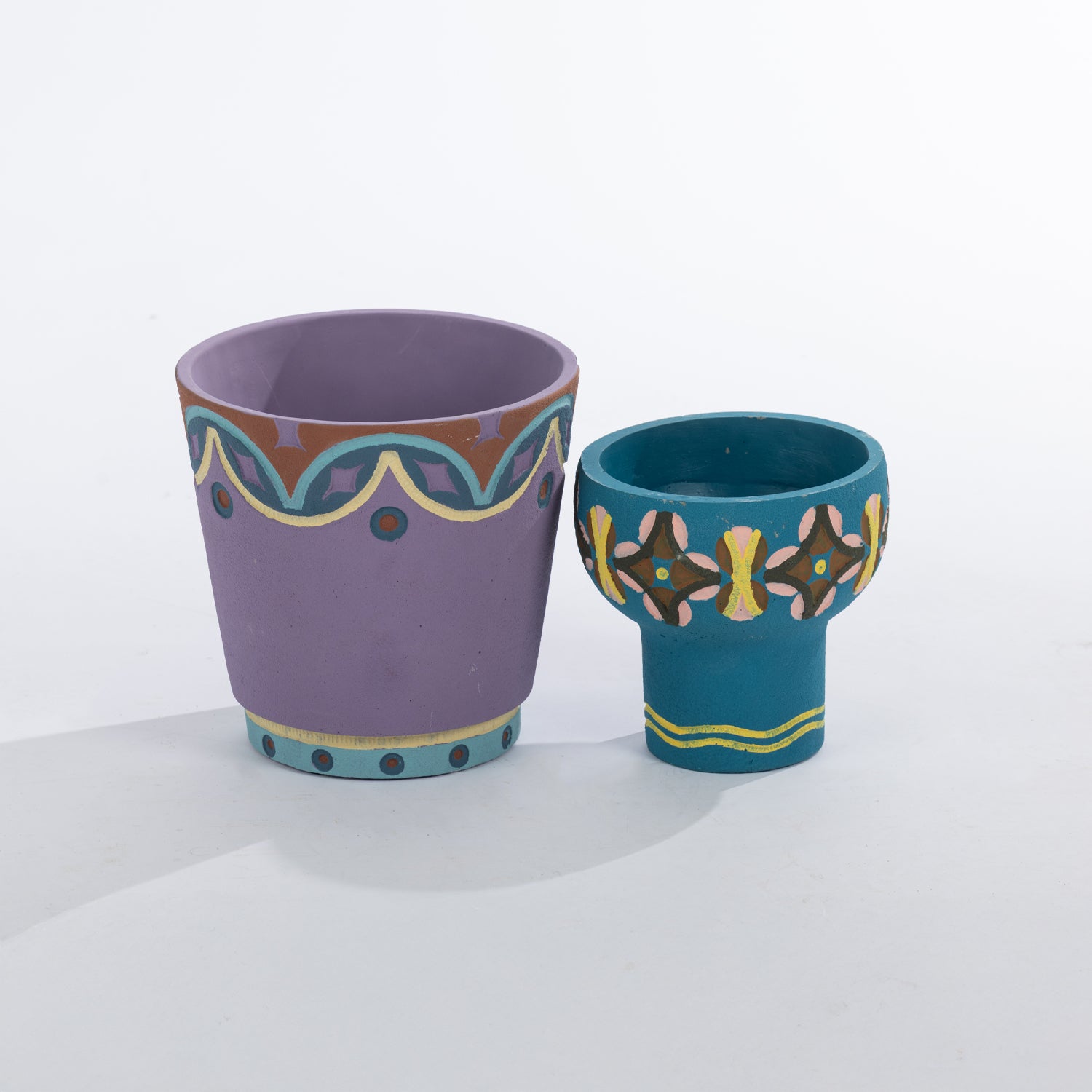 A pair of colourful painted planters featuring bold geometric patterns in lavender and teal brings vibrant, artisan-inspired style to any indoor or outdoor setting.