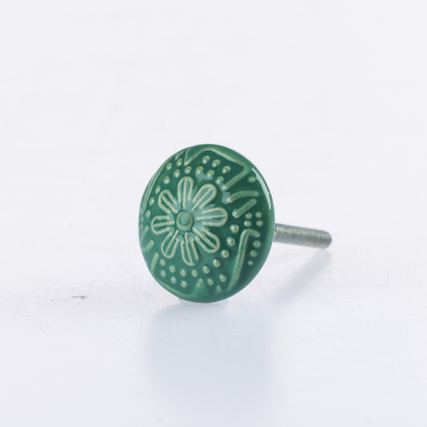 Green ceramic round drawer knob with embossed floral pattern detailing and metal screw fitting.