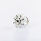 White flower-shaped ceramic drawer knob with taupe leaf detailing and silver metal centre accent.
