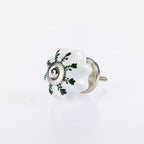 White flower-shaped ceramic drawer knob with green leaf detailing and silver metal centre accent.
