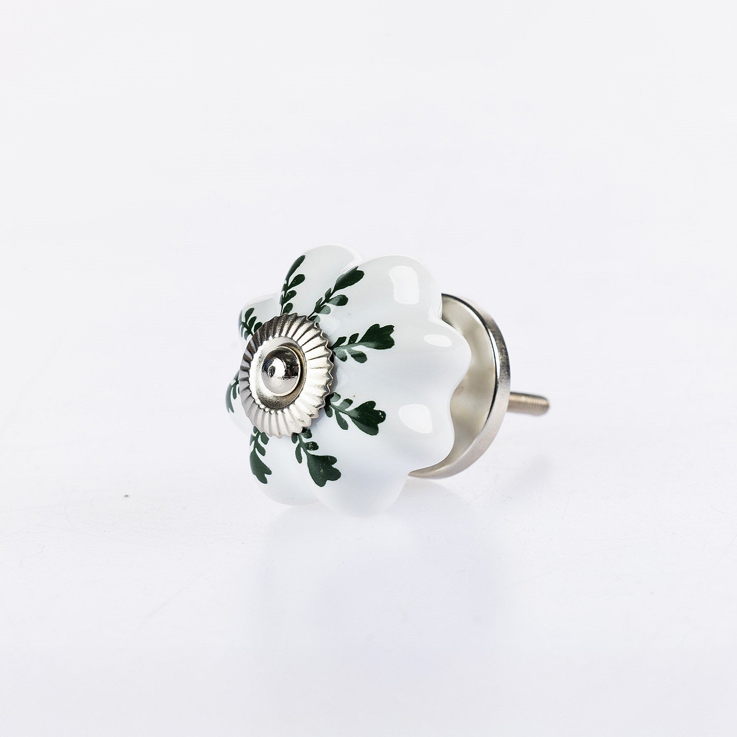 White flower-shaped ceramic drawer knob with green leaf detailing and silver metal centre accent.
