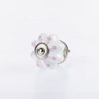White flower-shaped ceramic drawer knob with soft pink leaf detailing and silver metal centre accent.
