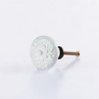 White ceramic round drawer knob with embossed floral pattern detailing and metal screw fitting.
