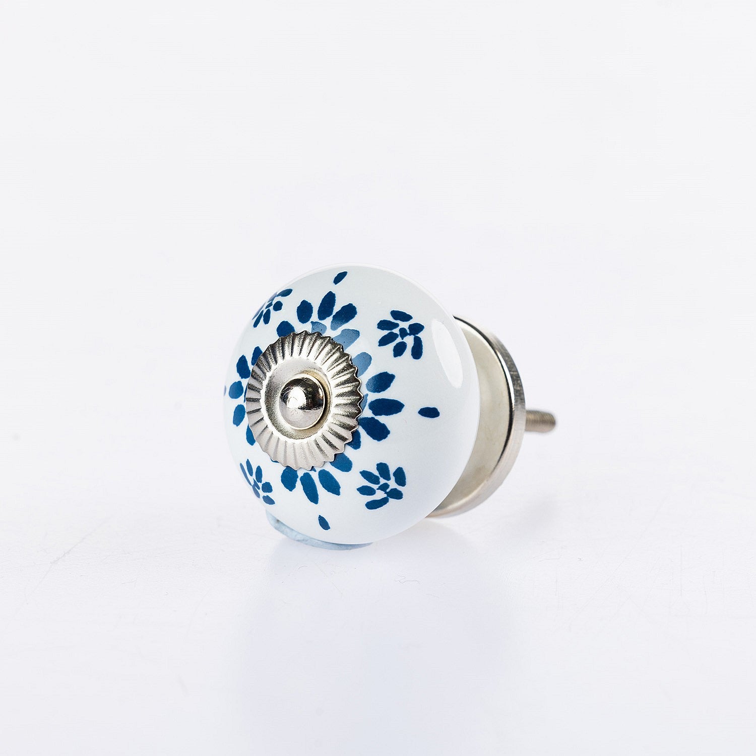 White ceramic round drawer knob with blue floral lace pattern detailing and silver metal centre accent.
