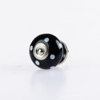 Black ceramic round drawer knob with pale blue polka dot detailing and silver metal centre accent.
