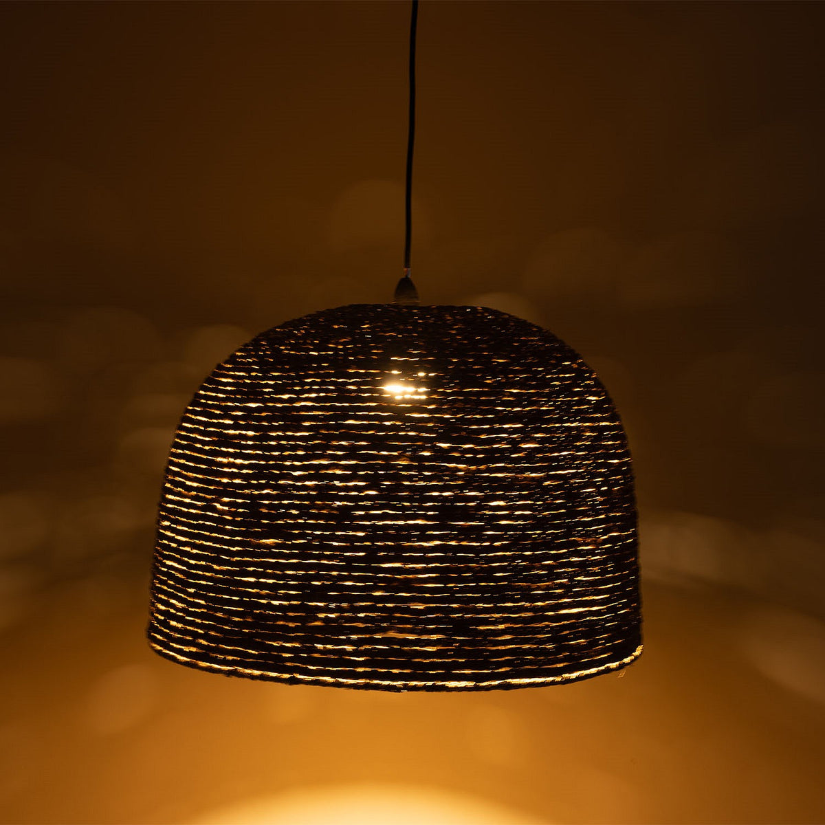 Woven pendant light casting a warm glow against a dark background