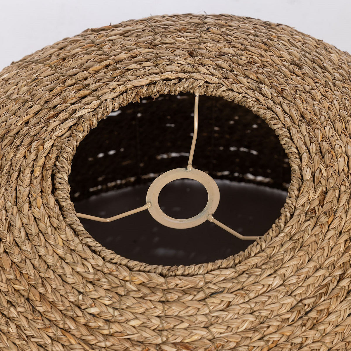 Close-up of a woven lampshade with a black interior and visible wiring.