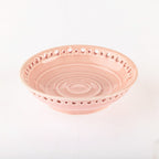 A light pink ceramic bowl with a decorative perforated rim and concentric ring patterns inside, shown on a plain white background.