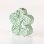 A small ceramic flower-shaped vase in a glossy pale mint green glaze, photographed on a clean white background.