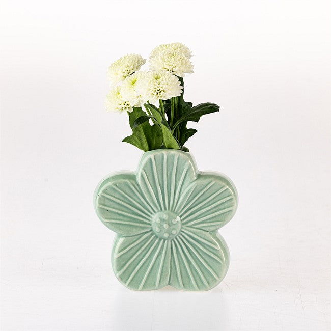 A light green ceramic flower-shaped vase with a ribbed center and five petals, holding white flowers with green stems, set against a plain white background.