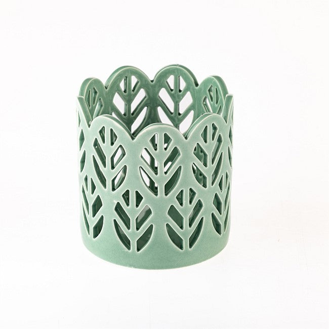 A sage green ceramic candle holder with a leaf cutout pattern, set against a plain white background.