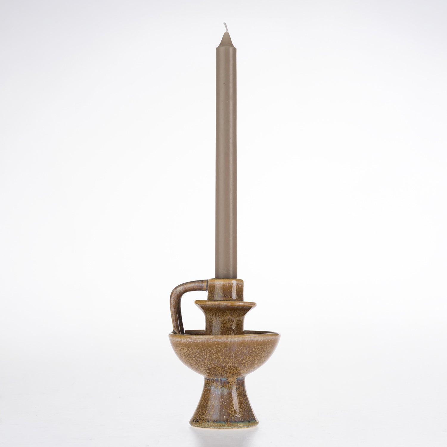 Brown ceramic candle holder with a rounded bowl-shaped base, pedestal foot and curved handle, styled with a taupe taper candle.