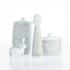 Cove Malaya décor pieces styled together, including the large urn, candle holder, decorative bottle, and elephant ornament in coordinating white textured finishes with carved arch detailing.