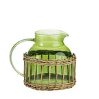 Design Republique Millie small green glass jug with a curved handle, pouring spout and woven rattan-style wrap around the base.