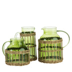 Design Republique Millie green glass pitchers in assorted sizes, featuring curved handles, pouring spouts and woven rattan-style wraps around the bases.