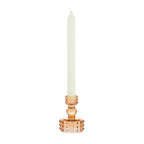 Amber glass candle holder with raised bubble detailing, holding a tall cream taper candle on a white background.