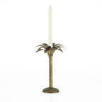 Pewter palm tree candle holder with a tall ivory tapered candle on a white background.
