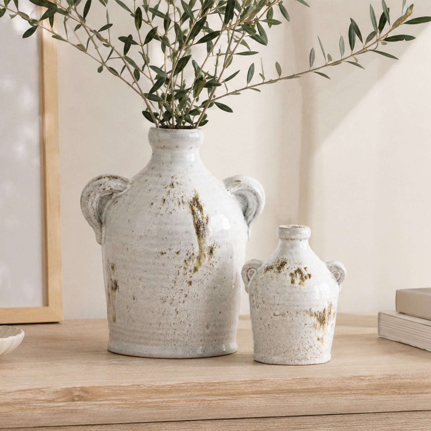 Large and small Cove Franco Ceramic Ears Vases displayed together on a wooden console, with the large vase holding olive branches.