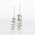 Small and large flower-shaped candle holders with white taper candles on a white background.