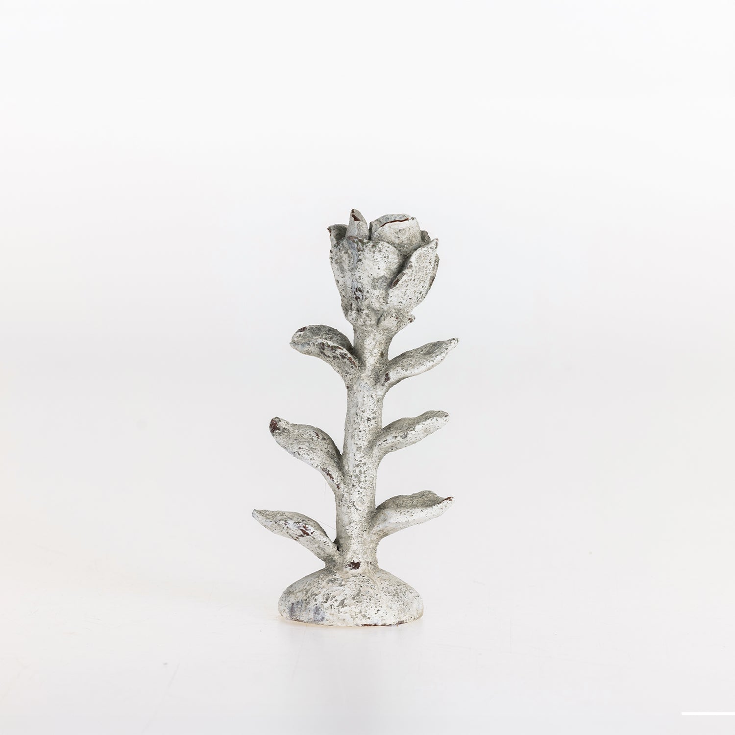 Small flower-shaped candle holder with a white taper candle on a white background.