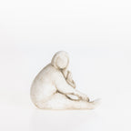 Abstract ceramic lady resting figurine in a natural stone-look finish on a white background.