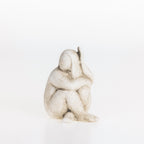 Abstract ceramic lady figurine in a natural stone-look finish seated in a contemplative pose on a white background.