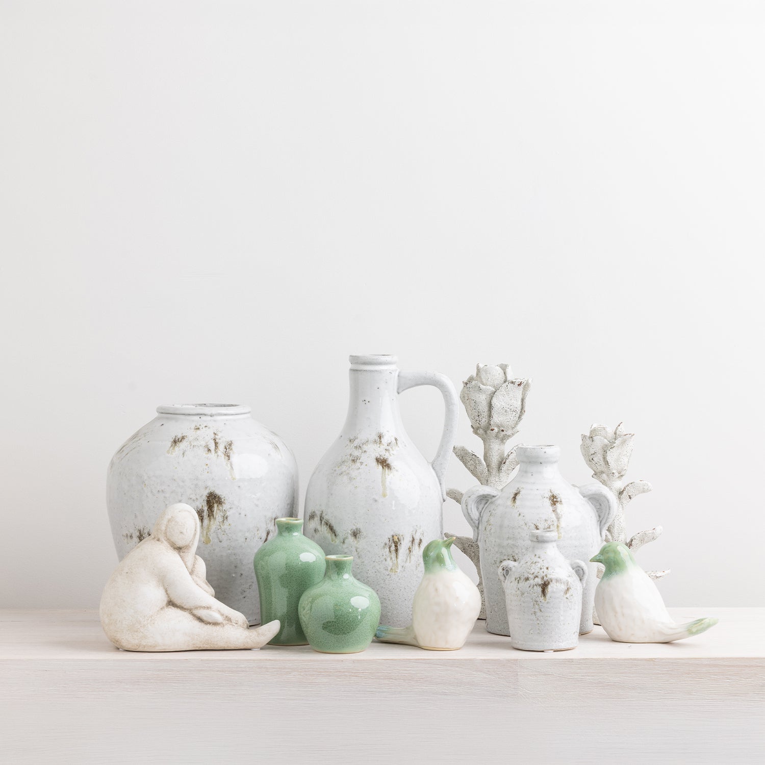 The Cove Franco ceramic lady figurines styled on a wooden console with coordinating décor including vases, artwork and greenery.