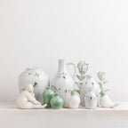 The Cove Franco ceramic lady figurines styled on a wooden console with coordinating décor including vases, artwork and greenery.