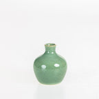 Small glossy green ceramic bud vase with a rounded body and narrow neck displayed on a white background.