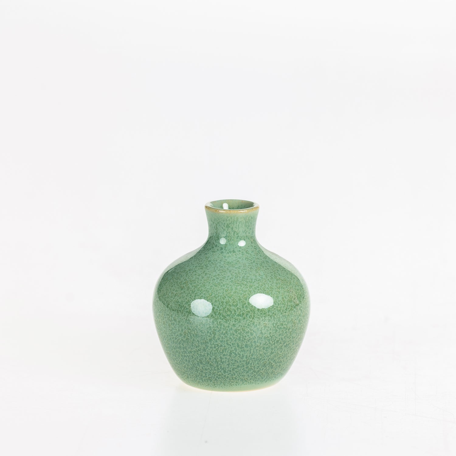 Small glossy green ceramic bud vase with a rounded body and narrow neck displayed on a white background.