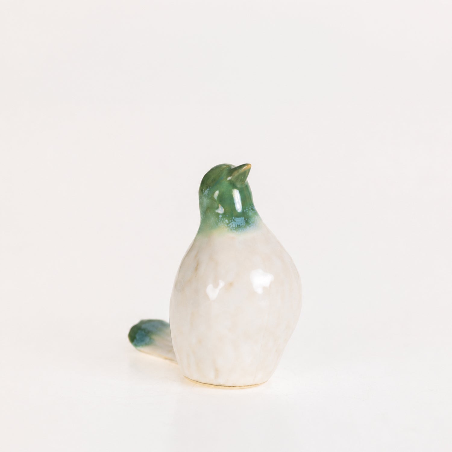 Glossy green and white ceramic bird figurine with an upright pose displayed on a white background.