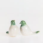 Two glossy ceramic bird figurines with green heads and tails and white bodies displayed together on a white background.